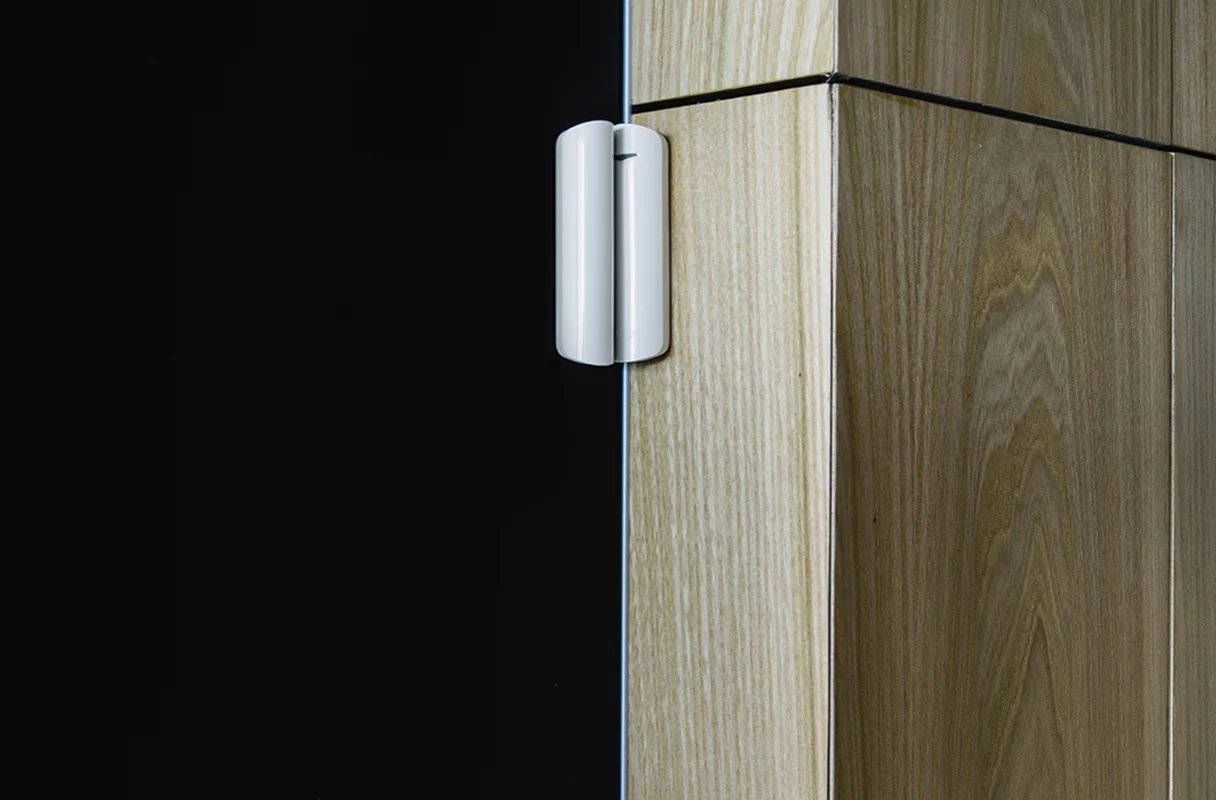 Détecteur d’ouverture Ajax DoorProtect sur une porte, visuel officiel du fabricant